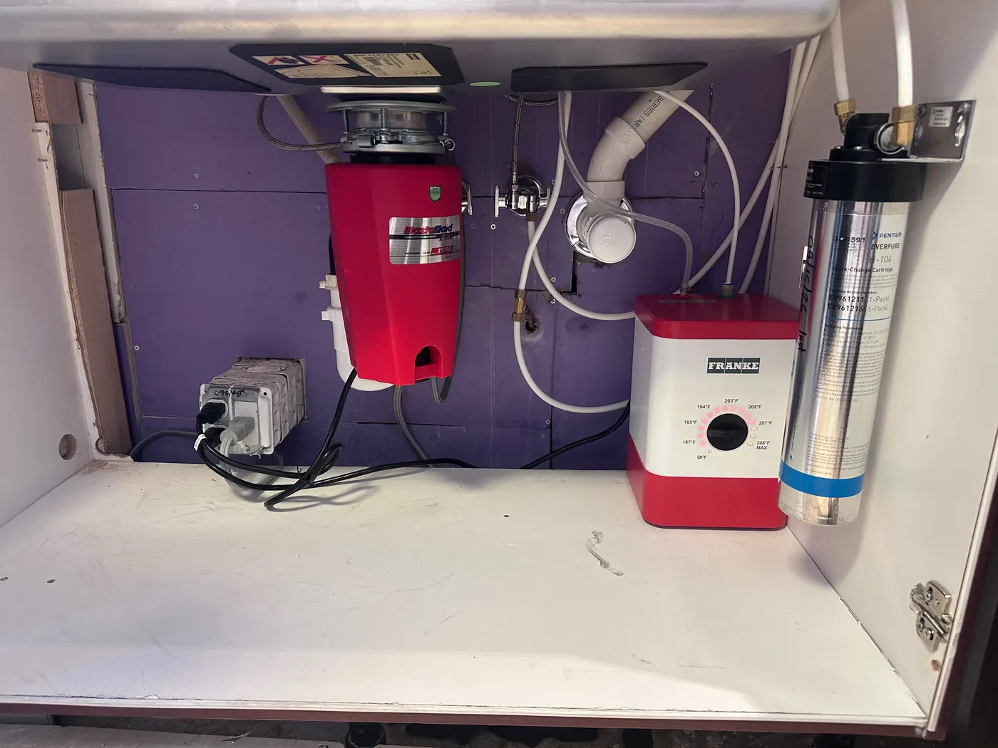 A new garbage disposal and water filter installed under a kitchen sink